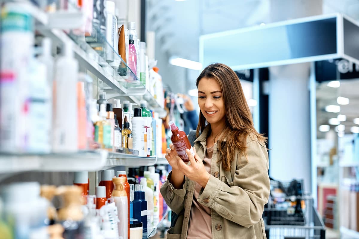 Beauty-Products-Young-happy-woman-reading-ingredients-of-skin-care-product-while-shopping-at-the-store