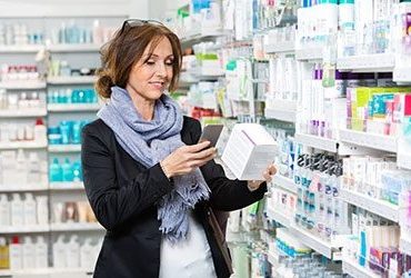 FIRST-COLUMN-Smiling-female-customer-scanning-product-through-cell-phone-in-pharmacy-1